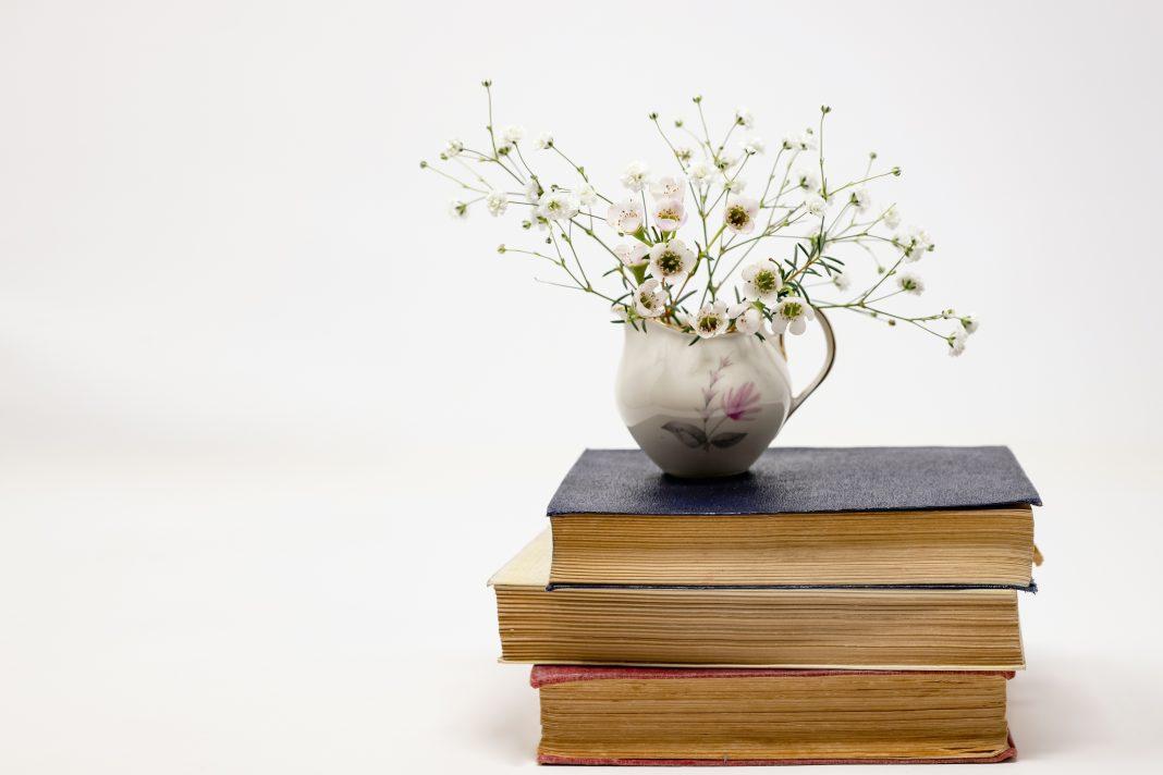 Stack of books with flowers in vase on top | 3 Latina Authors