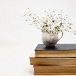 Stack of books with flowers in vase on top | 3 Latina Authors