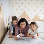 Grandmother and grandchildren on bed reading a book | Read Across America Week