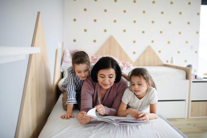 Grandmother and grandchildren on bed reading a book | Read Across America Week