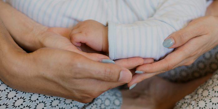 mom hands and dad hands holding a baby