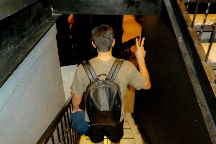 Young man with backpack walking down steps with a peace sign made on his hands | Firstborn: A Latina Mom’s Reflection on Parenting, Growth, and Letting Go