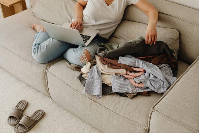 woman sitting on couch with laptop and laundry next to her | My Best Looks Different Every Day: A Real Take on Motherhood