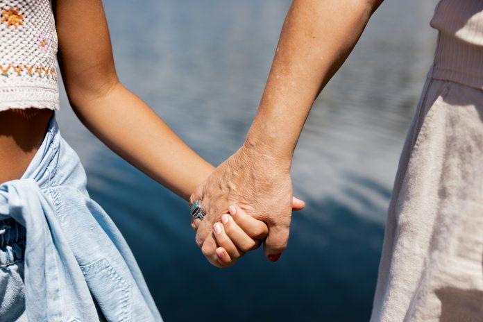 younger girl holding hands with old mom