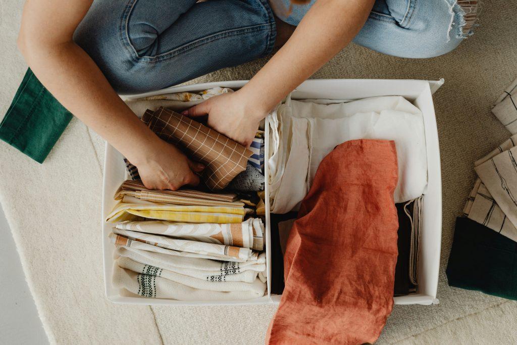 Woman organizing clothes in bin | Capsule wardrobe for kids