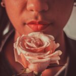 Woman with red lips holding pink rose in front of her face | February, but make it Paquita & Jenni