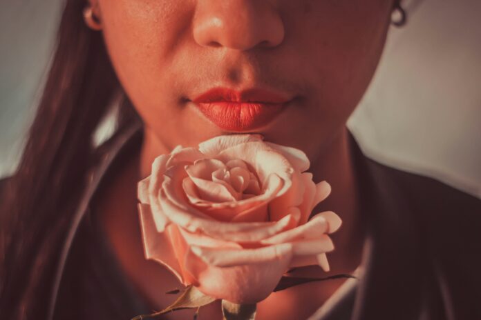 Woman with red lips holding pink rose in front of her face | February, but make it Paquita & Jenni