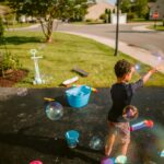 Easy Spring Activities for Kids (Simple Ideas for Moms) little boy playing with bubbles in his driveway