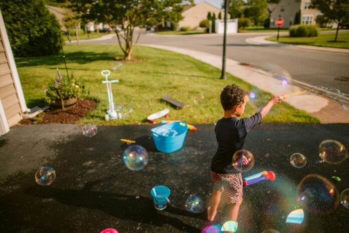 little boy playing with bubbles in his driveway