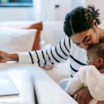 Working Mom Guilt: What I’ve Learned About Balancing Career and Motherhood mom holding baby while working at a desk on a computer